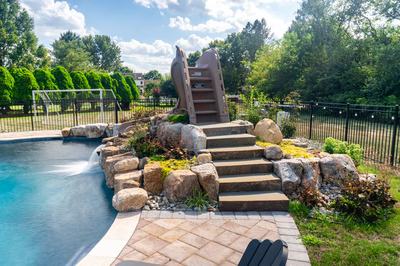 Shomyo G - Princeton Junction, NJ - A backyard with a swimming pool and a play structure surrounded by lush greenery