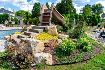 Shomyo H - Princeton Junction, NJ - A backyard with a rock garden and a play structure next to a swimming pool