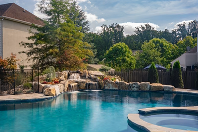Sipi B - Pikesville, MD - A swimming pool with a waterfall in the middle surrounded by lush greenery