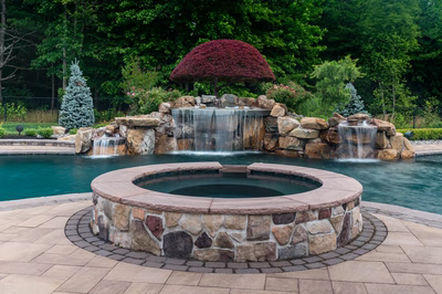 Sisiyi N - Manalapan, NJ - A beautiful outdoor swimming pool with a waterfall and a fire pit surrounded by lush greenery