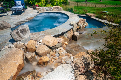 Spirit L - Cream Ridge, NJ - A backyard with a swimming pool surrounded by rocks and a waterfall