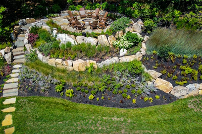 Spirit R - Cream Ridge, NJ - A circular stone fire pit surrounded by lush greenery and a stone path leading to it