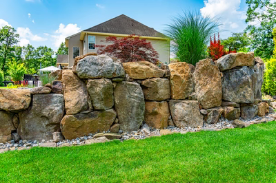 Spray H - Franklinville, NJ - A large rock wall in a backyard with a house in the background