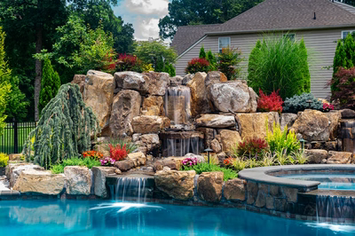 Spray K - Franklinville, NJ - A beautiful backyard with a waterfall feature surrounded by lush greenery and colorful flowers