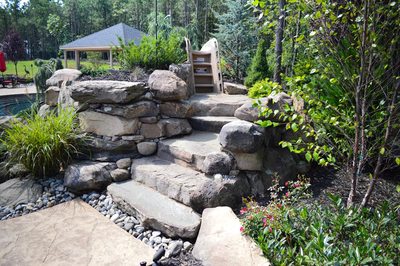 Sutherland F - Monroe, NJ - A stone retaining wall with steps leading up to a gazebo surrounded by greenery and flowers