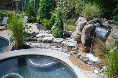 Sutherland G - Monroe, NJ - A backyard with a small waterfall and a pool surrounded by greenery