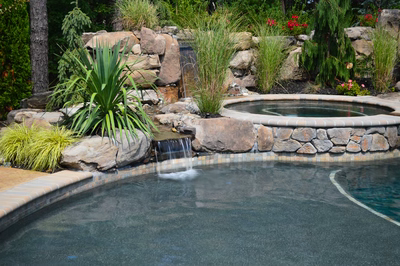 Sutherland H - Monroe, NJ - A swimming pool surrounded by lush greenery and a waterfall.