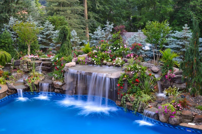 Tama B - Manalapan, NJ - A swimming pool with a waterfall surrounded by lush greenery and colorful flowers