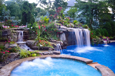 Tama E - Manalapan, NJ - A swimming pool with a waterfall surrounded by lush greenery and colorful flowers