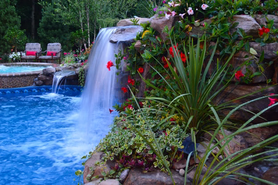 Tama J - Manalapan, NJ - A waterfall cascades down a rocky cliff into a pool surrounded by lush greenery and colorful flowers