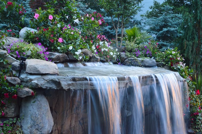 Tama M - Manalapan, NJ - A small waterfall surrounded by colorful flowers and rocks in a garden