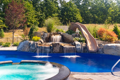 Tamolitch B - Millstone, NJ - A swimming pool with a waterfall and a slide surrounded by lush greenery