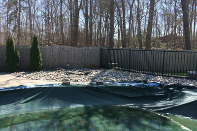 Tana A - Bayville, NJ - A backyard with a fence and a green tarp covering a pool area.