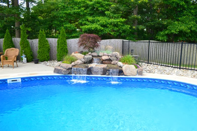 Tana B - Bayville, NJ - A swimming pool with a waterfall in the middle surrounded by trees and a fence
