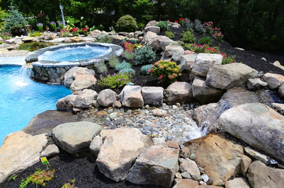 Tanner D - West Windsor, NJ - A rock garden with a waterfall and a hot tub surrounded by flowers