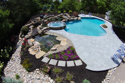 Tanner G - West Windsor, NJ - A beautiful backyard with a swimming pool surrounded by lush greenery and colorful flowers
