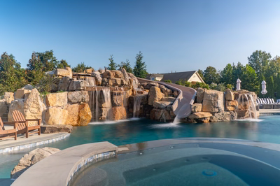 Tchupala C - Medford, NJ - A large pool with a waterfall and a slide in the middle of it