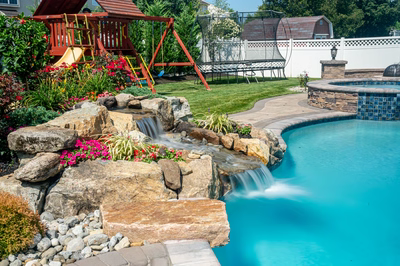 Thika E - Berlin, NJ - A backyard with a swimming pool, a play area, and a waterfall