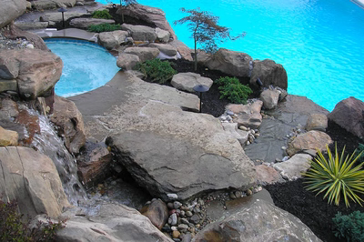 Tiger C - Sicklerville, NJ - A swimming pool surrounded by rocks and plants with a waterfall.