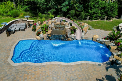 Toketee K - Galloway, NJ - A swimming pool with a waterfall and a water slide surrounded by lush greenery