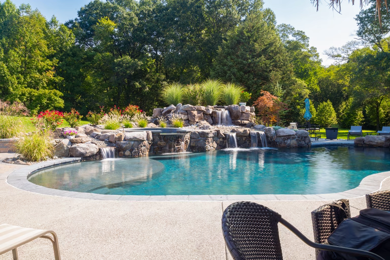 Boulder waterfall cascading into a freeform pool surrounded by lush garden plants