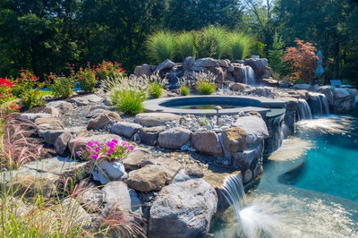 Tufa D - Medford, NJ - A beautiful backyard with a waterfall and a pool surrounded by lush greenery and colorful flowers