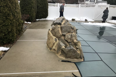 Tugela C - Sayreville, NJ - A large rock sitting on top of a concrete driveway next to a white fence