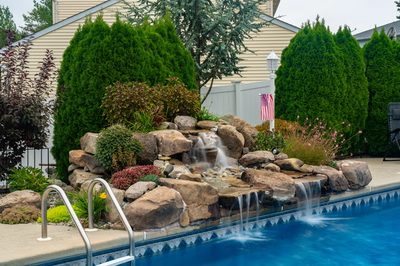 Tugela E - Sayreville, NJ - A swimming pool with a waterfall in the middle surrounded by plants and trees