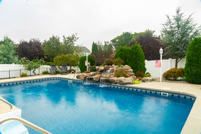 Tugela F - Sayreville, NJ - A blue swimming pool surrounded by lush greenery and a white fence