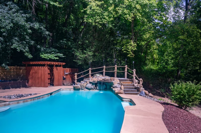 Vernal F - Media, PA - A blue swimming pool surrounded by lush green trees and a wooden fence