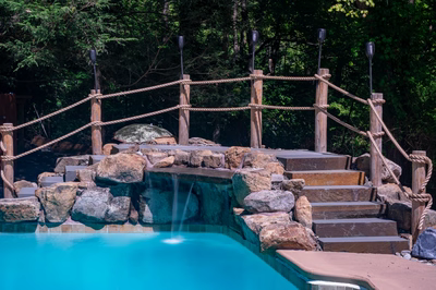 Vernal J - Media, PA - A wooden bridge over a small waterfall in a swimming pool surrounded by rocks and greenery