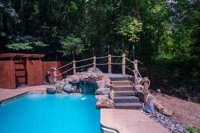 Vernal K - Media, PA - A swimming pool surrounded by lush green trees and a wooden fence.
