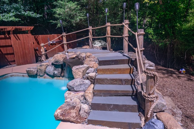 Vernal L - Media, PA - A wooden bridge over a rock waterfall over a swimming pool surrounded by lush greenery