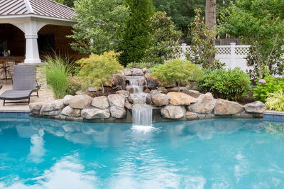 Victoria A - Stafford, NJ - A swimming pool with a waterfall in the middle surrounded by lush greenery