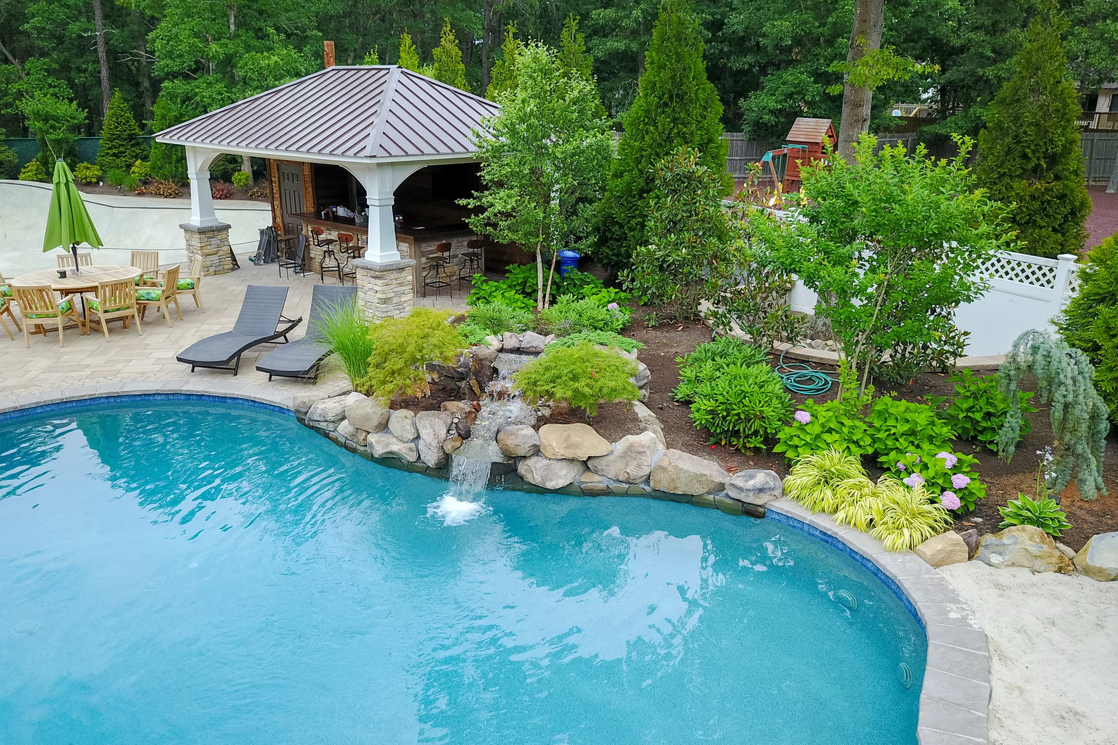 Natural stone boulder waterfall cascading into a blue pool surrounded by lush greenery