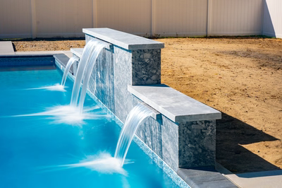 Waireinga B - Bel Air, MD - A blue swimming pool with a waterfall feature in the middle of it