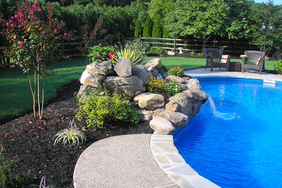 Wallaman B - Mt. Laurel, NJ - A backyard with a swimming pool surrounded by lush greenery and flowers