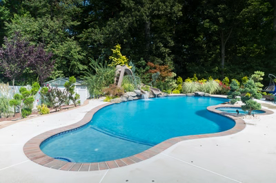 Wentworth C - Morganville, NJ - A swimming pool surrounded by lush greenery and colorful flowers, with a water feature in the center