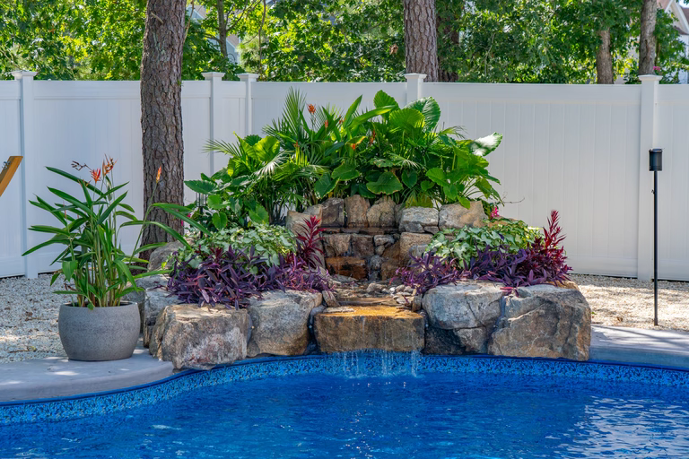 Natural stone boulder waterfall cascading into a pool surrounded by lush tropical landscaping