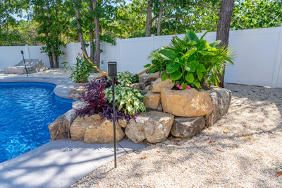 Willamette C - Barnegat, NJ - A rock retaining wall next to a swimming pool surrounded by lush greenery