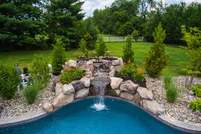 Willey B - Moorestown, NJ - A backyard with a swimming pool and a waterfall surrounded by lush greenery