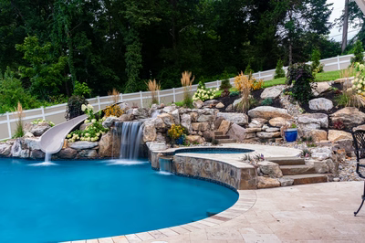 Yosemite H - Newtown Square, PA - A swimming pool with a waterfall and a waterfall feature surrounded by lush greenery