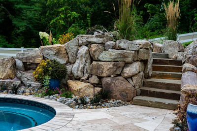 Yosemite L - Newtown Square, PA - A stone retaining wall next to a swimming pool with steps leading up to it