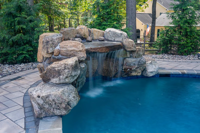 Zealand C - Lutherville, MD - A swimming pool with a waterfall in the middle surrounded by lush greenery