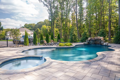 Zealand I - Lutherville, MD - A swimming pool surrounded by lush greenery and a stone waterfall.