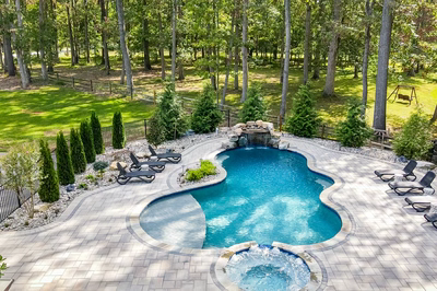 Zealand J - Lutherville, MD - A backyard with a swimming pool surrounded by lush greenery and trees