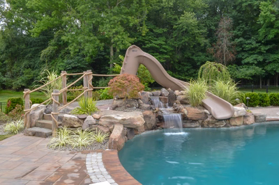 Zillie B - Manalapan, NJ - A pool with a water feature and a water slide in a backyard setting