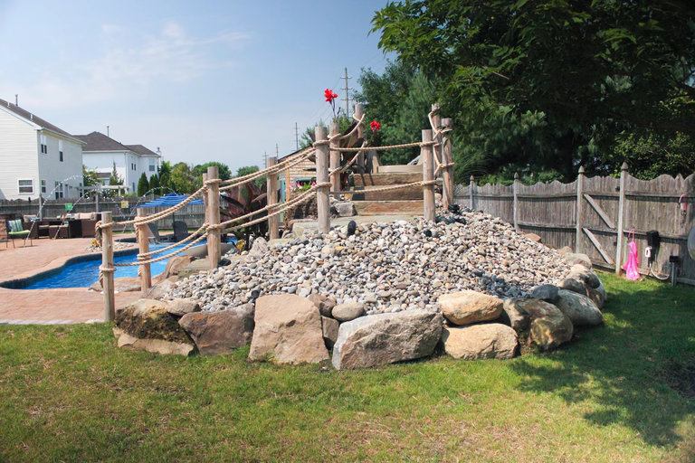 A backyard with a rock structure and a wooden fence surrounding it