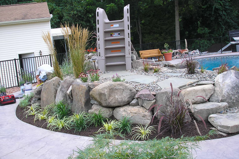 A landscaped area near a swimming pool with rocks and plants