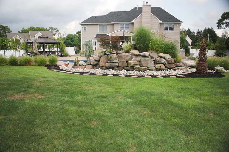 A large house with a stone wall in the middle of a lush green yard